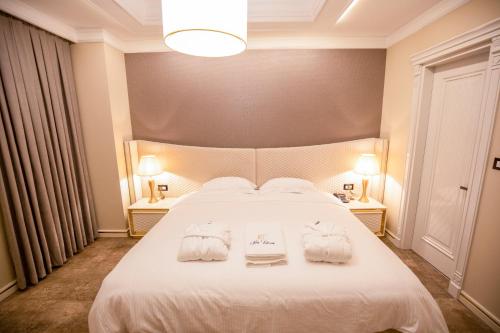 a bedroom with a white bed with towels on it at Vila EKREM in Korçë