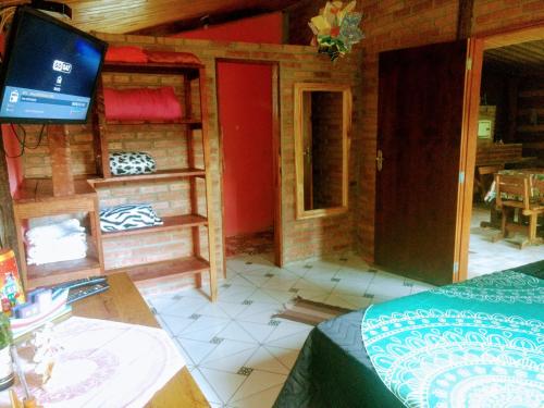 a room with a bed and a tv in a house at Chalé Vale das Flores - Visconde de Mauá Rj in Visconde De Maua