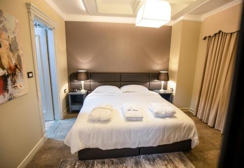 a bedroom with a large white bed with towels on it at Vila EKREM in Korçë