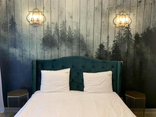 a bed with two pillows and two lights on a wall at Luxury Silver Mountain Apartment in Poiana Brasov