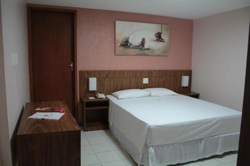 a bedroom with a large bed and a table at Steel Valley Economic Hotel in Ipatinga