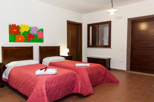 a bedroom with two beds with red sheets and white towels at Kikki Village in Modica
