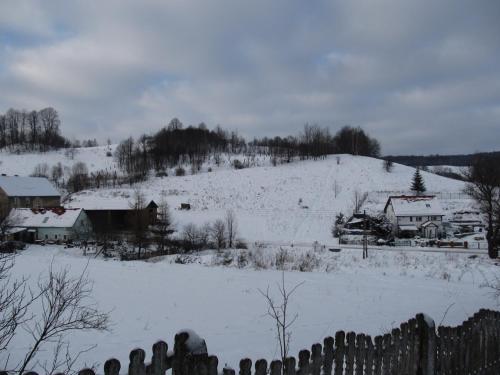 a snow covered field with houses and a hill at Chata za Górami in Zagórze Śląskie