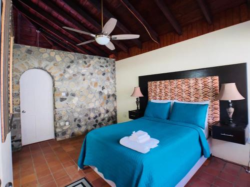 Schlafzimmer mit einem blauen Bett und einem Deckenventilator in der Unterkunft Stonetrail Villas in Arnos Vale