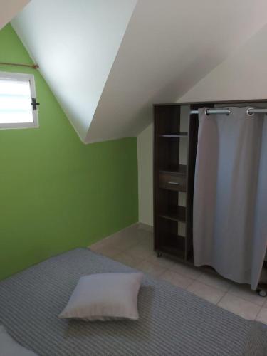 a room with a refrigerator and a green wall at Gîte Muskad in Sainte-Anne
