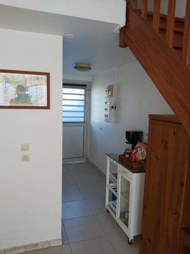 a kitchen with a staircase and a table in a room at Gîte Muskad in Sainte-Anne