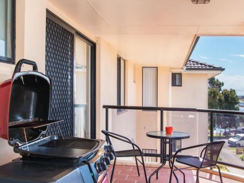 a balcony with a stove and a table and chairs at Horizons 8 on the lake in Forster