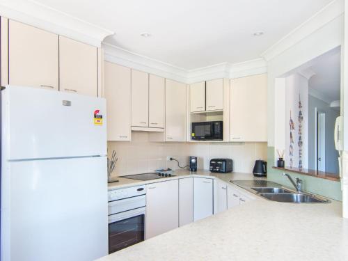 a kitchen with white cabinets and a white refrigerator at Horizons 8 on the lake in Forster