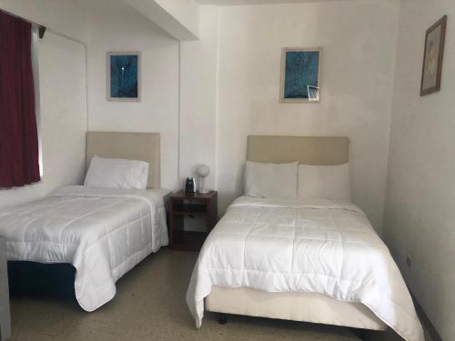 two beds in a room with white sheets at Coral Garden Hotel in Rota