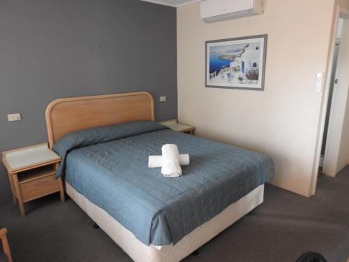 a bed with a white teddy bear sitting on it at Chelsea Motor Inn in Coffs Harbour