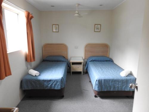 Habitación con 2 camas y ventana en Chelsea Motor Inn, en Coffs Harbour
