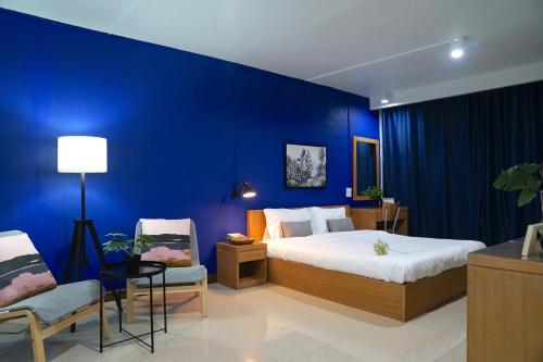 a blue bedroom with a bed and two chairs at The View Residence in Bangkok