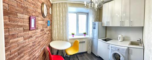 BelovoにあるАпартаменты на Юбилейной 5のレンガの壁のキッチン(テーブル、シンク付)