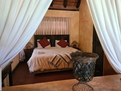 a bedroom with a bed with curtains and a table at Ndlovukazi River Chalets in Pongola