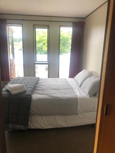 a bedroom with a large bed with two windows at Solway House in Alexandra