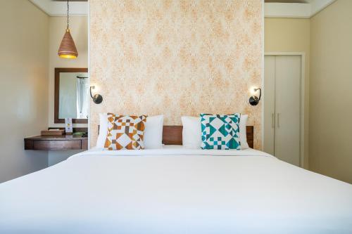 a bedroom with a large white bed with colorful pillows at Sai Kaew Beach Resort in Ko Samed