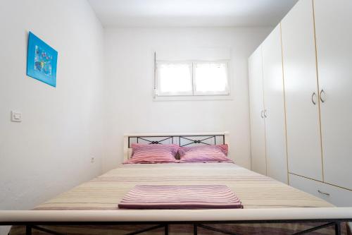 a bed with pink pillows in a white bedroom at Dimitra Beach Apartments - Thassos Skala Potamias in Skala Potamias