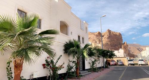 a white building with palm trees next to a street at Luxury fully furnished villa ڤيلا مؤثثة in AlUla