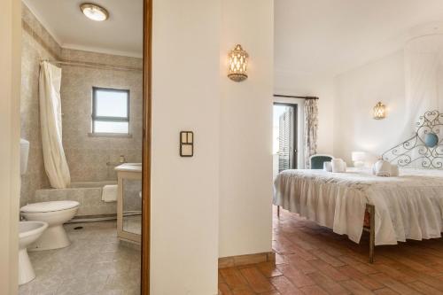 a bedroom with a bed and a tub and a toilet at Casa da Ermida in Budens