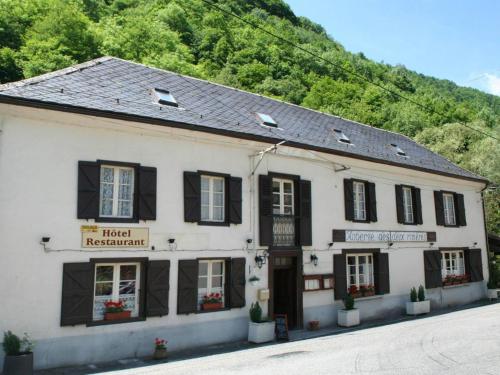 un bâtiment blanc avec volets noirs dans une rue dans l'établissement Auberge des Deux Rivières, à Seix