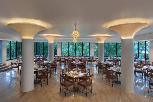 ein Esszimmer mit Tischen, Stühlen und einem Kronleuchter in der Unterkunft Earl's Regency Hotel in Kandy