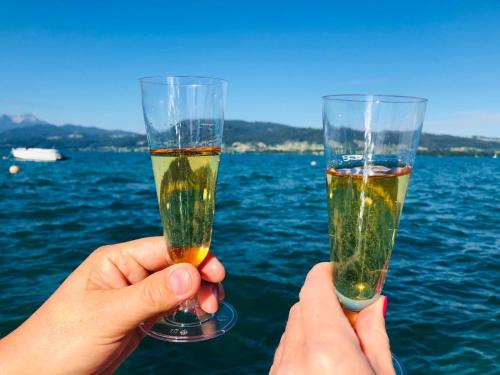 two people holding champagne glasses in front of the water at Ferienwohnungen Jodlbauerhof in Weyregg