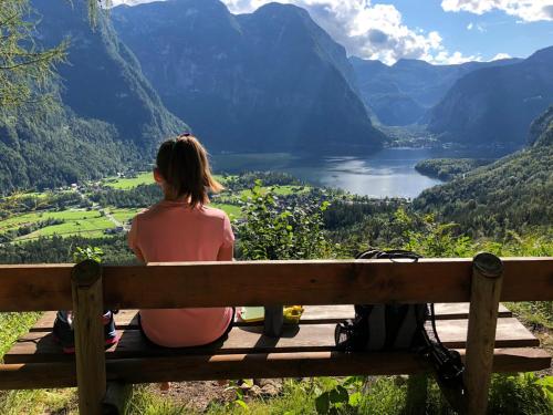 a woman sitting on a bench looking out over a valley at Ferienwohnungen Jodlbauerhof in Weyregg