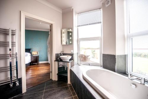 a bathroom with a bath tub and a bedroom at The Woolacombe Bay Hotel in Woolacombe