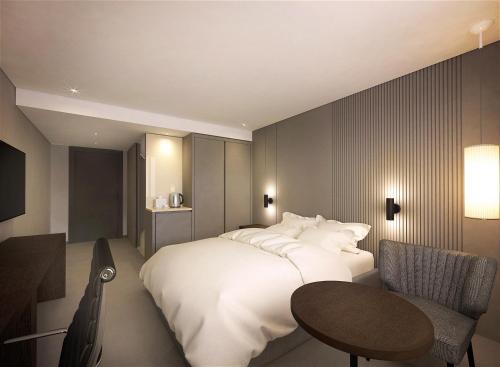 a bedroom with a bed and a table and a chair at Crown Hotel Changwon in Changwon