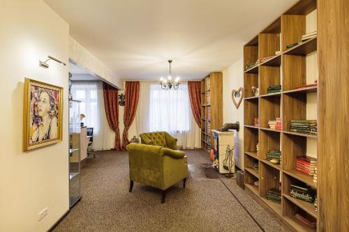 uma sala de estar com uma cadeira verde e prateleiras de livros em Art Hotel Bohema, Klaipėda em Klaipėda