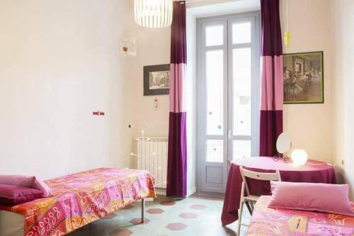 a room with two beds and a table and a window at Casa Dani&Swing Bed&Books in Turin