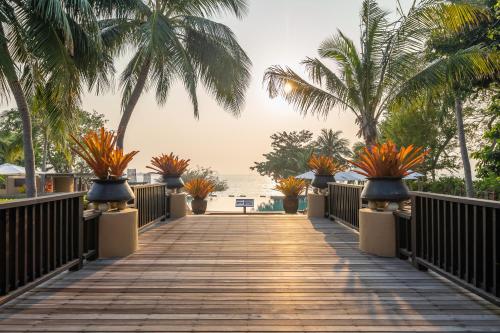 a wooden walkway leading to the beach with palm trees at Paradee in Ko Samed