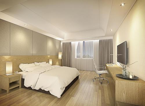a bedroom with a bed and a desk and a television at Crown Hotel Changwon in Changwon