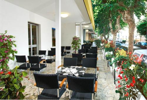 una fila de mesas y sillas en un patio con flores en Hotel Tura en Bellaria-Igea Marina