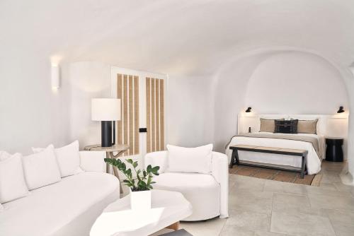 a white living room with a bed and a white couch at Charisma Suites in Oia