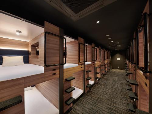 東京にあるSmart Stay SHIZUKU Shinagawa-Oimachiの多くの二段ベッドと木製の壁が備わる客室です。