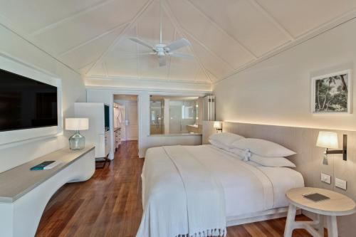 a white bedroom with a bed and a ceiling fan at LUX* Le Morne Resort in Le Morne