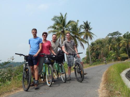 a group of people standing with bikes on a road at Alamanda Family Villas, Pool & Local Tours in Yogyakarta