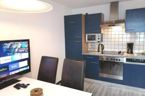 a kitchen with blue cabinets and a table with chairs at Dimai House No 17 Dornbirn Zentrum in Dornbirn
