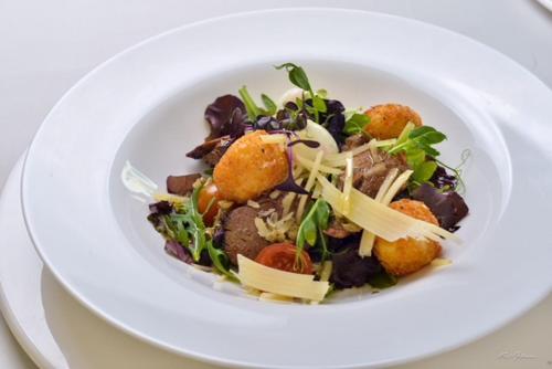 a white plate with a salad on a table at ibis Styles Pitesti Arges in Piteşti