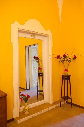 a yellow room with a mirror and two tables with flowers at B&B Dimora San Vincenzo in Gallipoli