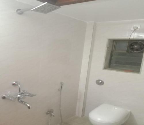 a white bathroom with a toilet and a window at Kuber's Residency in Mahad