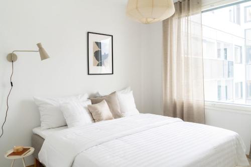 ein weißes Schlafzimmer mit einem weißen Bett und einem Fenster in der Unterkunft Roost Hämeenkatu in Tampella