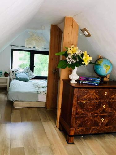 a bedroom with a bed and a vase of flowers on a dresser at Agroturystyka Przylesie in Wolimierz