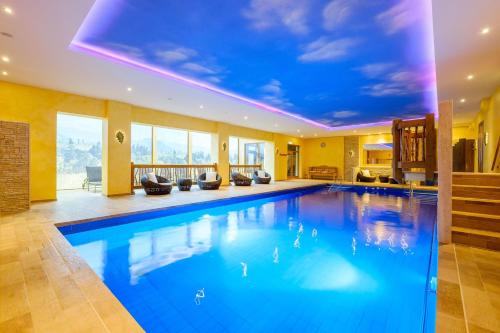 a large swimming pool in a house with a blue ceiling at Tanne Tonbach - Wellness & Wohlfühl Hotel in Baiersbronn