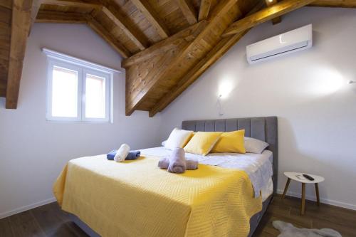 a bedroom with a yellow bed with two stuffed animals on it at Apartmani Klara in Stomorska