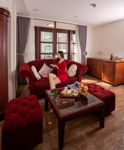 a woman sitting on a couch in a living room at Apus Hotel in Nha Trang