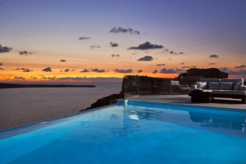 a pool with a view of the ocean at sunset at Charisma Suites in Oia