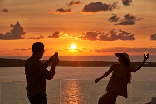 a man and woman taking pictures of the sunset at Charisma Suites in Oia