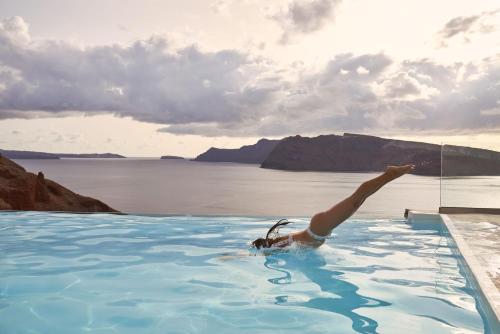 a person laying in a swimming pool in the water at Charisma Suites in Oia